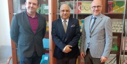 The photograph shows three men standing side by side: Dr. Michał Wiśniewski, Honorary Consul of Poland in Kolkata, Joydeep Roy, and Deputy Director for Programmes, Łukasz Galusek.