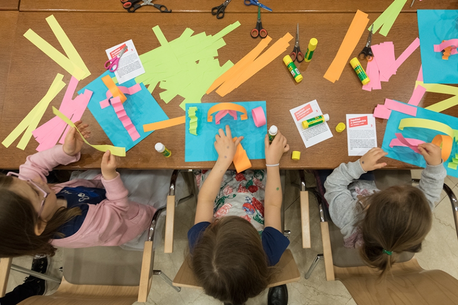 A colorful photo showing children sitting at a table doing artwork.