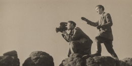 Sepia photography. The photo shows two men, one of them (Wlodzimierz Puchalski) is holding an old camera, the other is watching. 