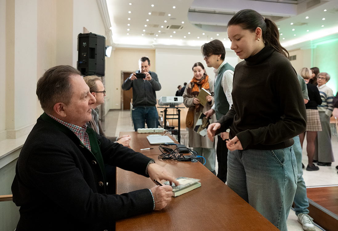 Robert Makłowicz i Maciej Czerwiński podpisują książki.
