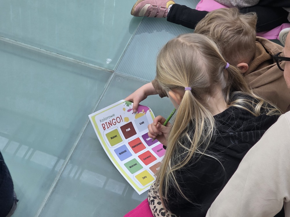 Dzieci wypełniają kartę Kolorowe Bingo podczas warsztatów edukacyjnych.