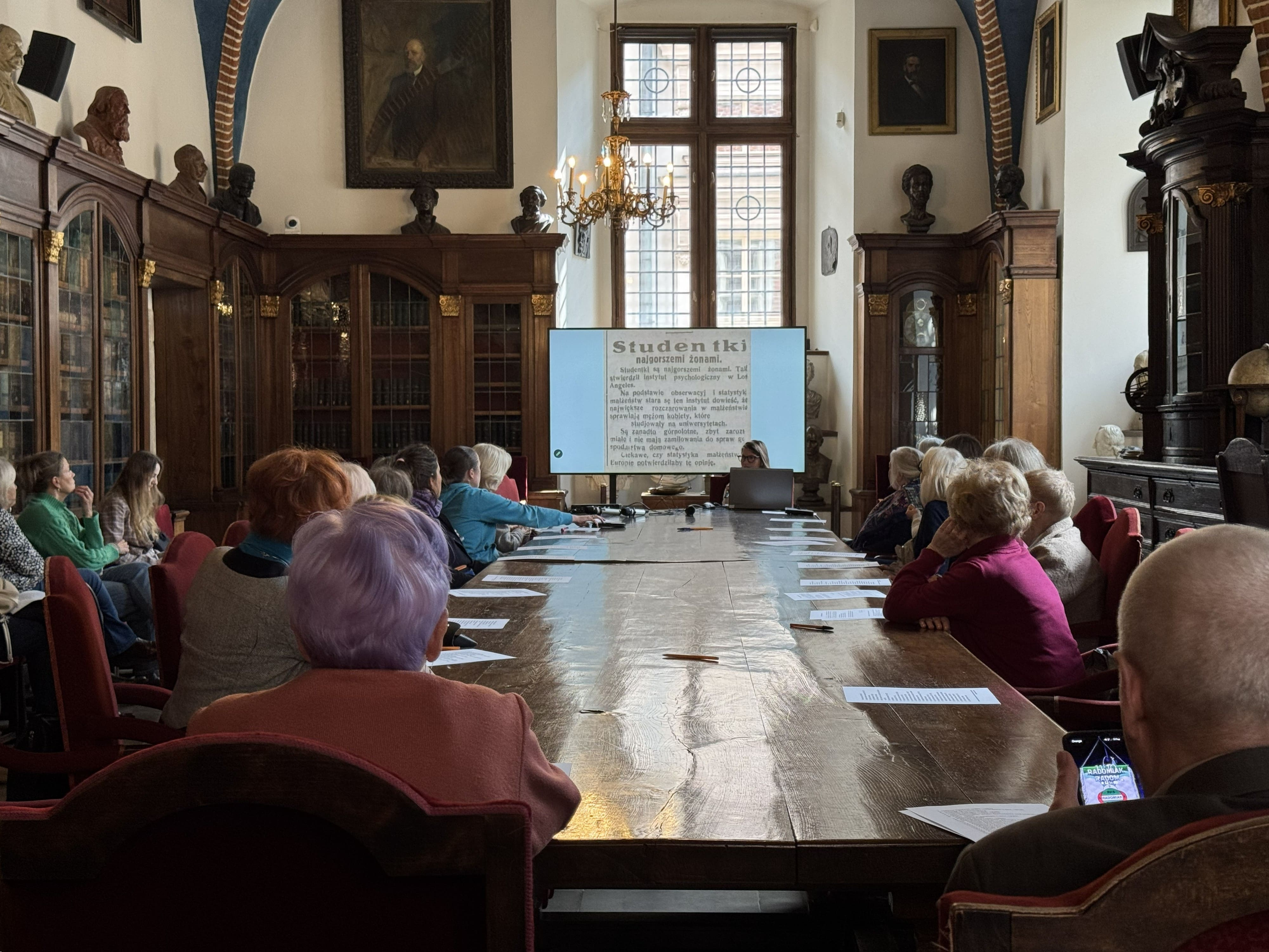 Sala Muzeum UJ. Uczestnicy wykładu siedzą za dużym stołem.