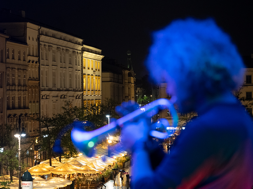 Petre Ionuțescu gra na trąbce w oknie. Widok na Rynek Główny nocą. 