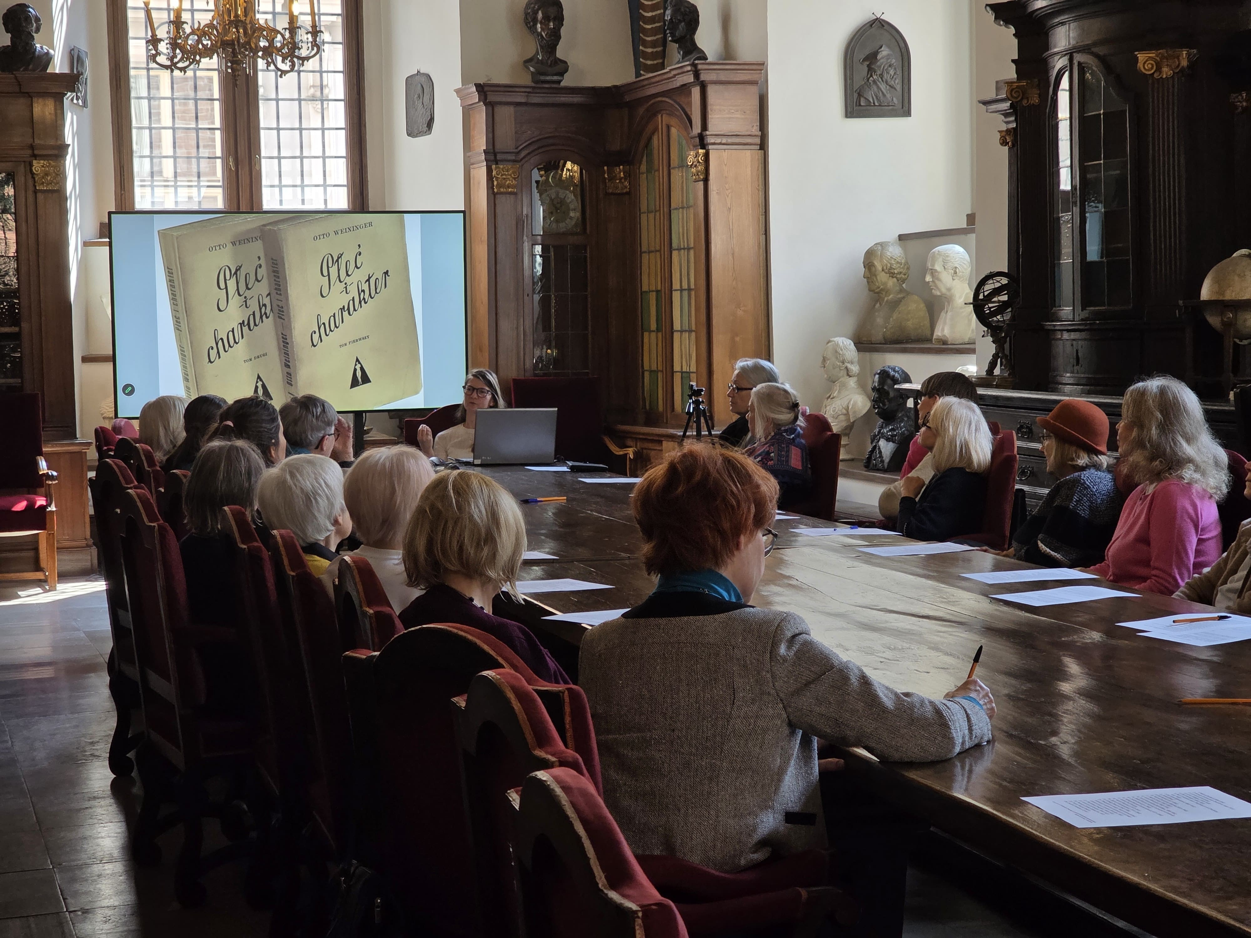 Sala Muzeum UJ. Za dużym stołe siedzą uczestnicy wykładu.