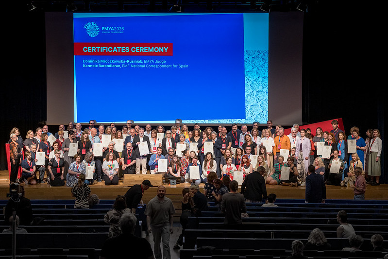 Uczestnicy ceremonii wręczenia certyfikatów podczas konferencji EMYA 2026 na scenie audytorium.