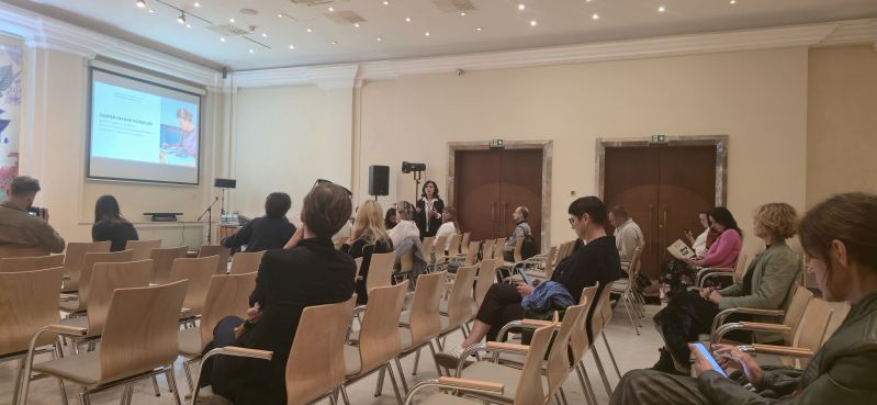 A speaker addresses participants in the Pod Kruki Hall at the International Cultural Centre. The screen shows a Ukrainian-language slide about digitising collections and documenting museum holdings.