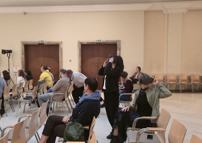 Participants test virtual reality headsets in the Pod Kruki Hall at the International Cultural Centre, while other attendees remain seated in the audience.