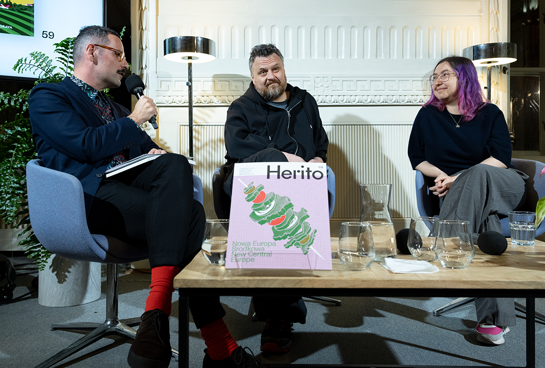 Bartosz Sadulski, Ziemowit Szczerek i Karolina Ćwiek-Rogalska podczas rozmowy wokół 60. numeru magazynu HERITO. Na pierwszym planie, na stoliku między uczestnikami, stoi egzemplarz numeru Nowa Europa Środkowa, obok karafki i szklanek z wodą.