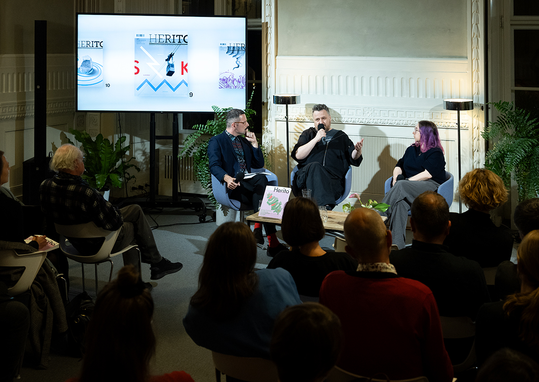 Bartosz Sadulski, Ziemowit Szczerek i Karolina Ćwiek-Rogalska podczas rozmowy poświęconej 60. numerowi magazynu HERITO. Ziemowit Szczerek przemawia do mikrofonu, a pozostali uczestnicy dyskusji słuchają; w tle na ekranie wyświetlone są okładki wcześniejszych numerów HERITO, a przed sceną siedzi publiczność.