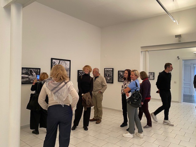 Zespół Międzynarodowego Centrum Kultury podczas wizyty studyjnej w Muzeum Sztuki w Ołomuńcu. Uczestnicy seminarium oglądają ekspozycję fotograficzną i rozmawiają w jasnej sali wystawowej, otoczeni czarno-białymi fotografiami prezentowanymi na ścianach.